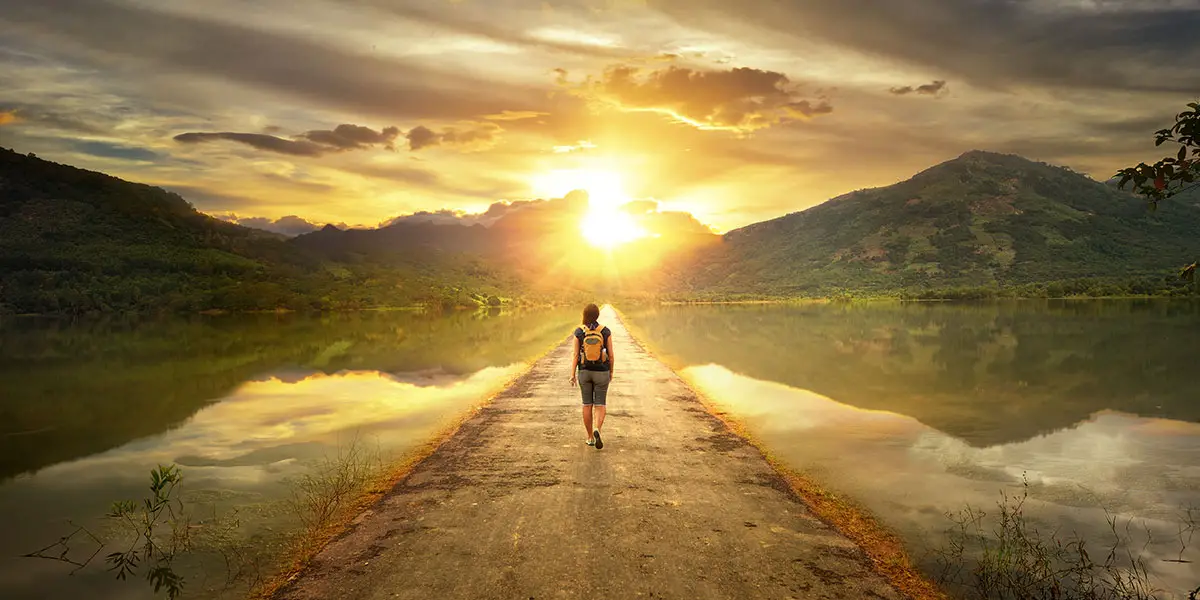 Person walking down a road at sunrise