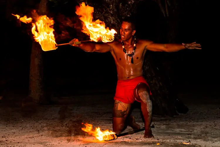 Polynesian man performs traditional fire dance in Tahaa