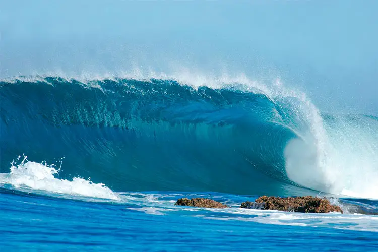 A beautiful blue wave crashes into the rocks at Inhaca Island