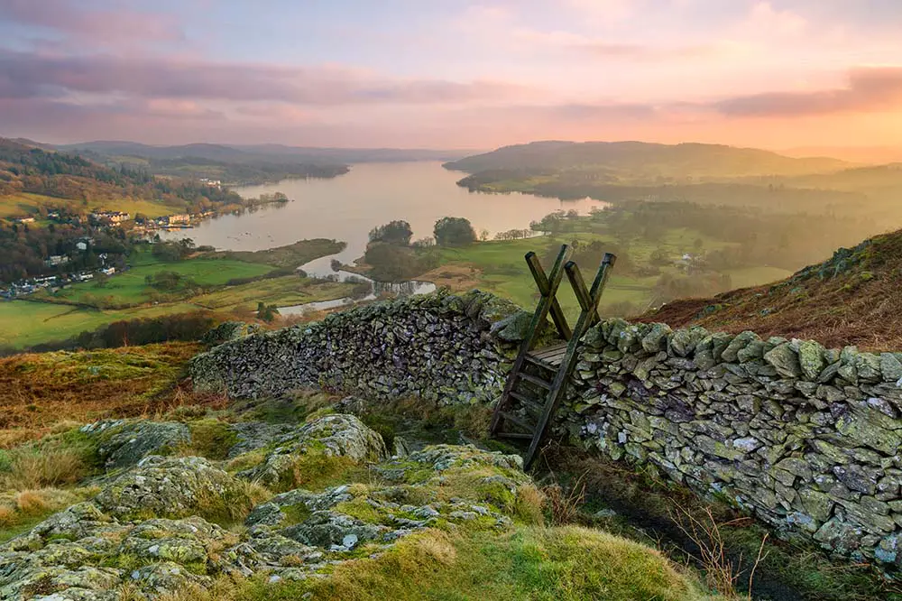 Beautiful sunset over Windermere in the Lake District with a stile and stone wall